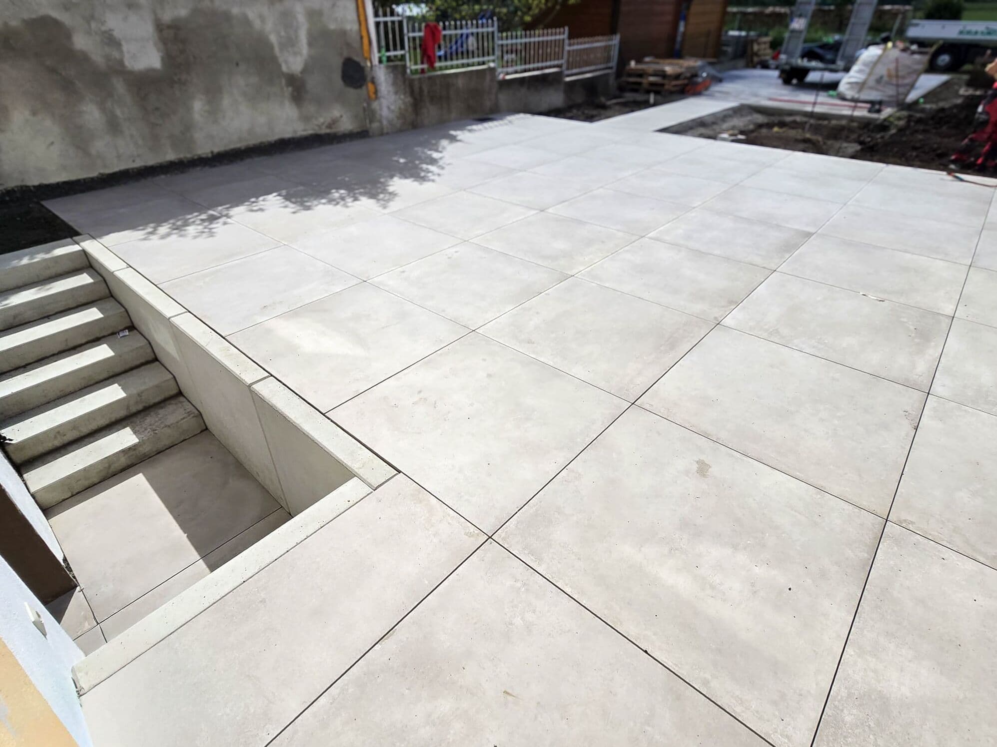 Terrasse aus Großformatplatten mit eingefasstem Kellerabgang
