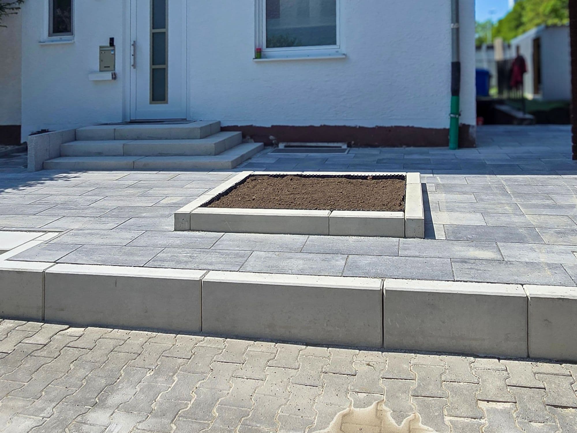Derselbe Vorplatz fertig gepflastert, mit Beet-Einfassung und Stufen